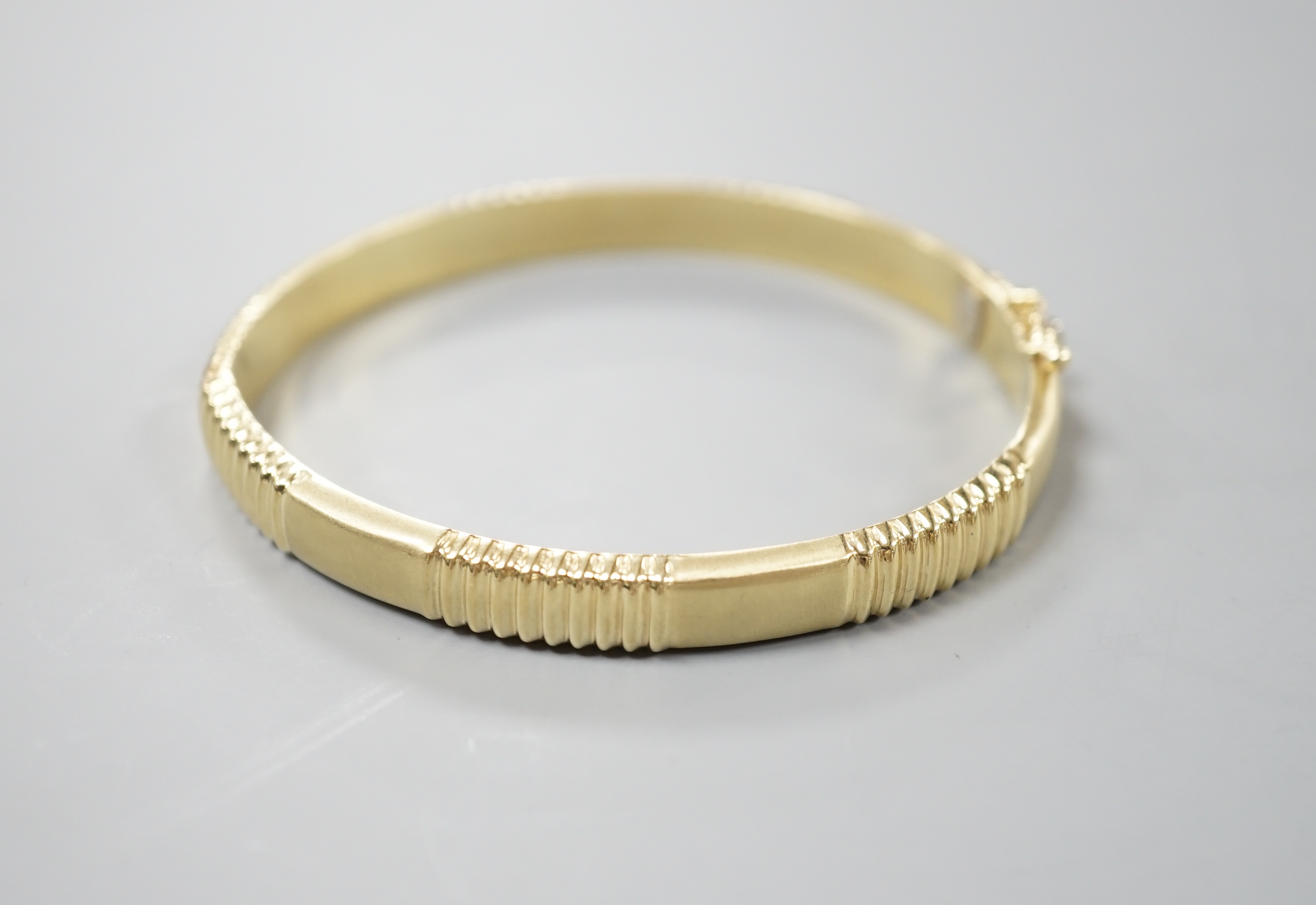 A modern 585 yellow metal hinged bangle, 12.8 grams.